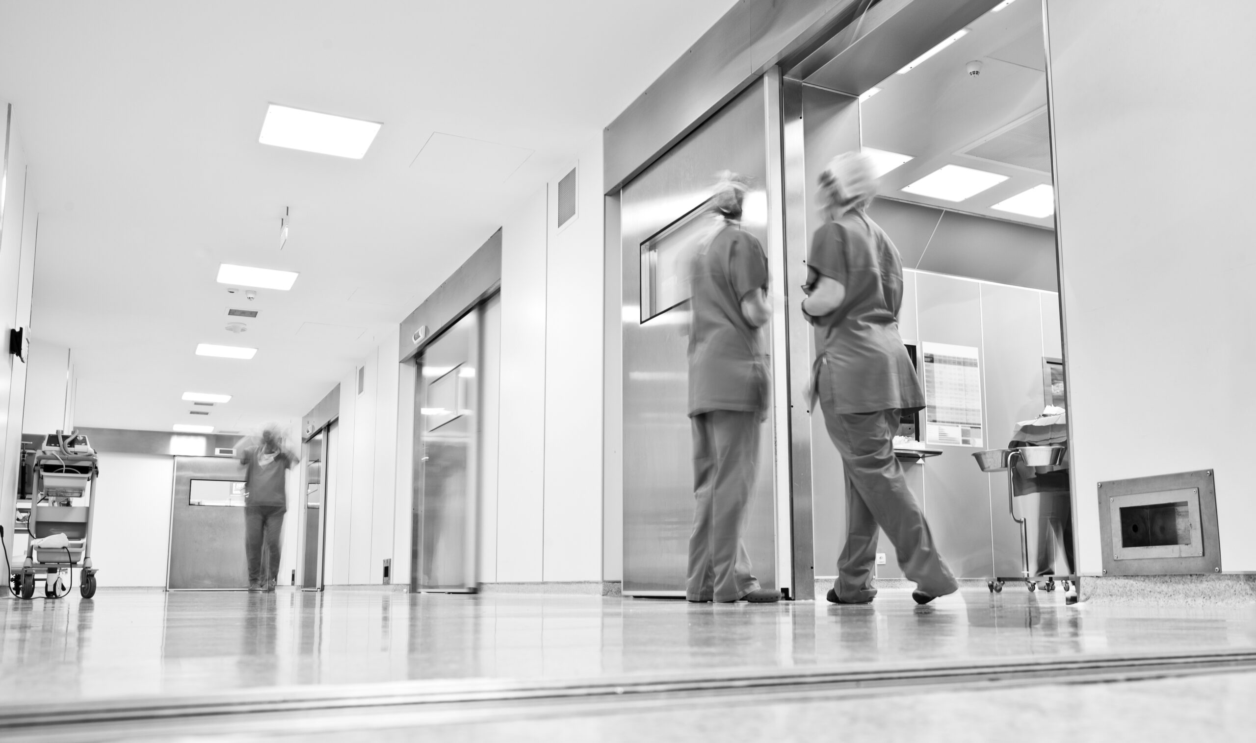 blurred figures wearing medical uniforms in hospital surgery corridor